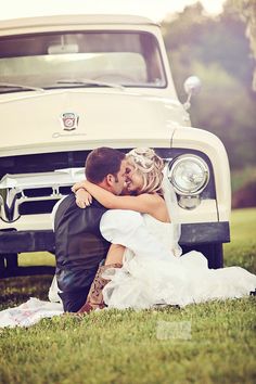 a bride and groom hugging in front of an old white truck on their wedding day