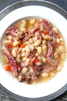 a white bowl filled with meat and beans on top of a blue cloth covered table