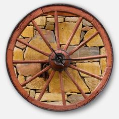 a clock made out of wood and stone with wheels on the front, sitting on a white wall