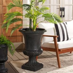 two black planters sitting on top of a wooden floor next to a white couch