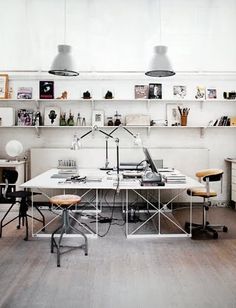 an office with two desks and shelves on the wall above them is shown in this photograph