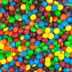 many different colored m & m candies are in the bowl on top of each other