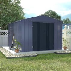 a blue shed sitting on top of a lush green field next to a white fence