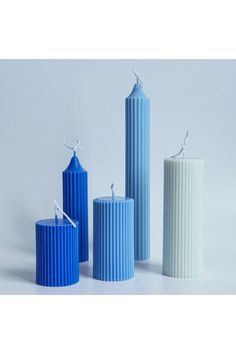 three blue and one white cylindrical candles on a white background with the candle in the middle