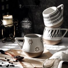 three white cups and spoons sitting on top of a table next to each other