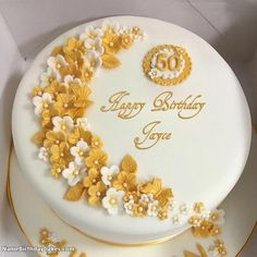 a 50th birthday cake decorated with flowers and gold trimmings on a white box