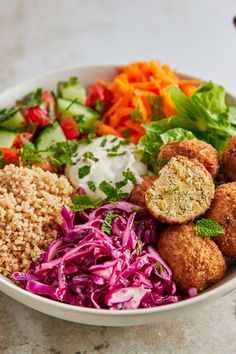 a white bowl filled with meatballs, coleslaw and carrots next to salad