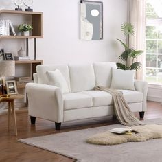 a white couch sitting on top of a hard wood floor next to a table and window