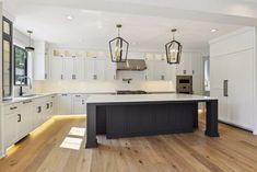 a large kitchen with an island in the middle of it and two pendant lights hanging from the ceiling