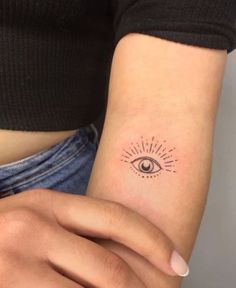 a woman's arm with a small tattoo on it that has an all seeing eye