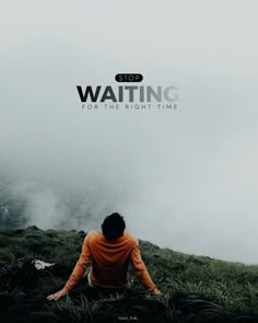 a man sitting on top of a lush green field next to a foggy mountain