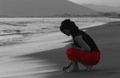 a woman kneeling down on the beach next to the ocean