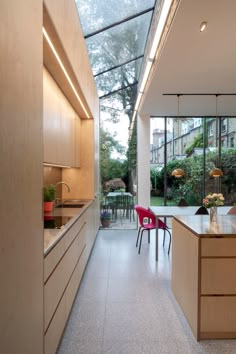 an open kitchen and dining area with skylights in the back ground floor to ceiling windows