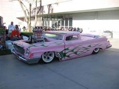 an old pink car with flames painted on it