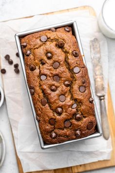 a loaf of chocolate chip banana bread sitting on top of a cutting board next to a knife