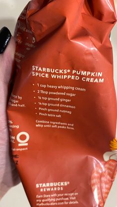 someone holding up a bag of starbuck's pumpkin spice whipped cream