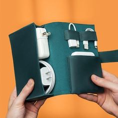 a hand holding an open green case with cords and plugs in it