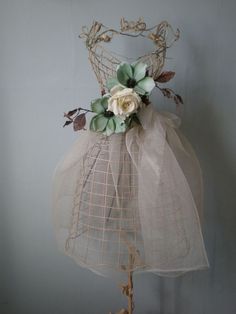 a mannequin is adorned with flowers and mesh for display on a table or wall