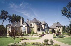 a large house with lots of trees in the front yard and landscaping on both sides