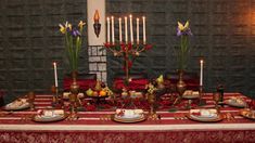 the table is set with candles, plates and fruit for an elegant dinner or party