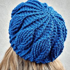 a woman with blonde hair wearing a blue knitted beanie on top of her head