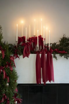 a mantle with candles and red bows on it