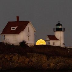 the moon is setting behind two white lighthouses