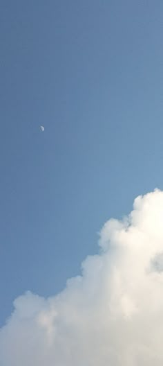 an airplane is flying high in the sky with a half moon behind it and some clouds