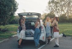 four girls are standing in the trunk of a car