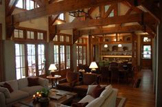 a living room filled with lots of furniture next to tall wooden beams on the ceiling