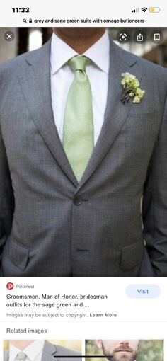 a man wearing a gray suit with a green tie and flower boutonniere