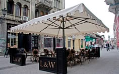 tables and chairs under an umbrella on the street