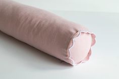 a pink pillow with scalloped edges on a white surface