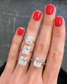 a woman's hand with three different rings on it and one has red nail polish