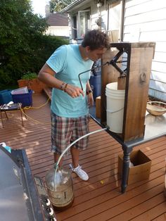 a man standing on top of a wooden deck next to a water tank and hose