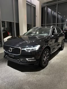 a black volvo car is on display in a showroom with other cars behind it