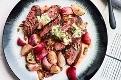 a plate with steak and potatoes on it next to a fork, knife and spoon