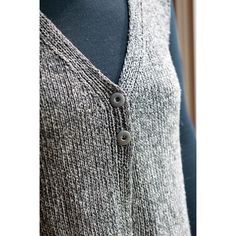 a woman's gray sweater with buttons on the front and back, next to a mannequin torso