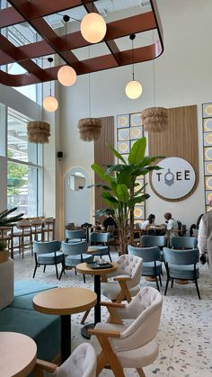 the inside of a restaurant with blue chairs and wooden tables in front of large windows