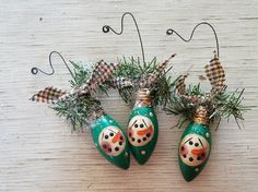 three christmas ornaments hanging from the side of a wooden table with snowmen on them