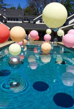 balloons floating in the air over a swimming pool