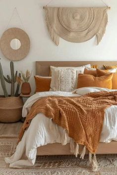 a bed with orange and white pillows in a bedroom next to a cactus plant on the wall