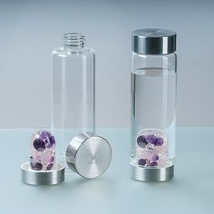 two glass bottles with different colored rocks in the bottom one is silver and the other is clear