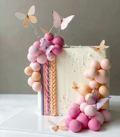 a white cake with pink and purple decorations on it's side, surrounded by butterflies