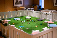 a baby crib filled with lots of toys on top of a green carpeted floor