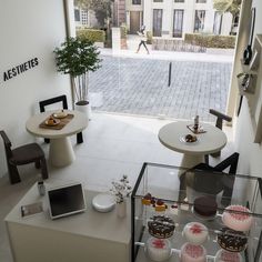 the interior of a bakery with cakes and pastries on display in front of an open door