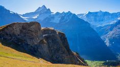 a suspension bridge on the side of a mountain with snow capped mountains in the background