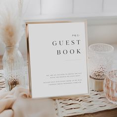 a guest book sitting on top of a table next to two glasses and a vase