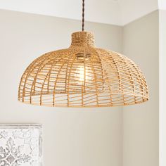 a rattan light fixture hanging from a ceiling in a room with white walls and flooring