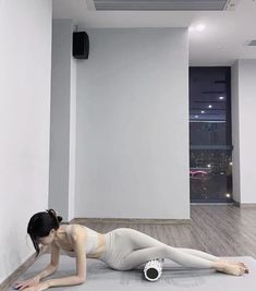 a woman laying on the floor in front of a white wall with an electronic device